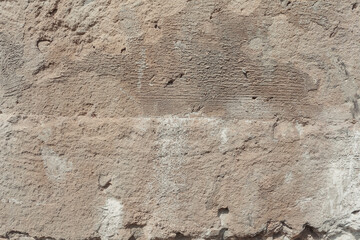 A stone surface with damages. Weathered old wall with detailed texture. Beige background texture.
