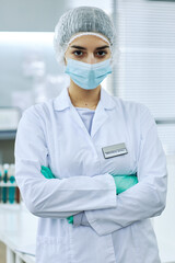 Vertical Portrait of Middle Eastern female scientist standing in medical laboratory and posing with arms crossed