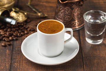 Turkish coffee in classic coffee cup with water and Turkish delight on wooden table