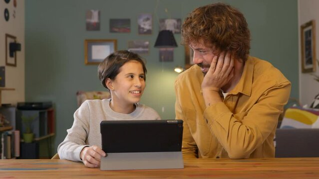 Father and daughter laughing and playing on digital tablet smiling relaxed family relationship