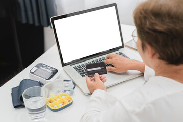 Telemedicine concept, senior asian woman Entering credit card information to laptop, paying bills online medical, Blank white screen with clipping path.