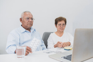 Telemedicine concept, male and female senior Asian couple Using laptop, video call with doctor to listen to advice and make a diagnosis.