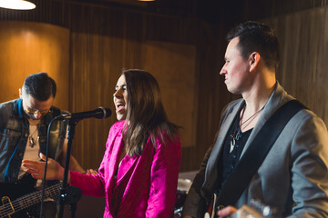 Band recording a new album. Indoor medium closeup shot of band consisting of three caucasian adults...