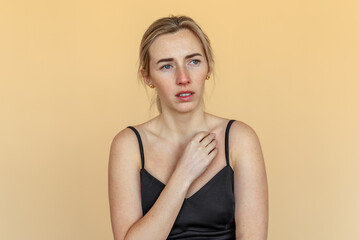 Fototapeta premium Portrait of the thoughtful upset woman standing over beige background, lost in thoughts. Pensive unhappy girl feeling lonely and depressed, thinking about relationship or personal problems