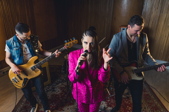 Stylish musicians in recording studio. High angle shot of four members of a music band. Stylish female caucasian singer looking at camera. High quality photo