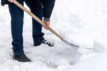 A man cleans snow with a metal shovel