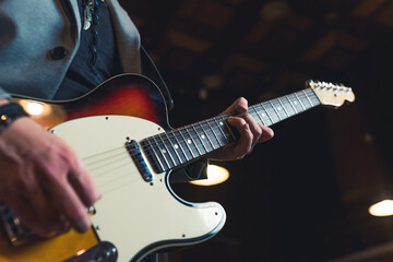 Guitarist and guitar. Closeup indoor shot of unrecognizable caucasian man playing with his hands on an electric guitar. High quality photo