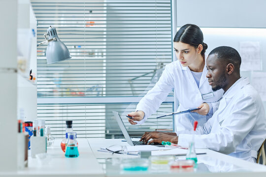 Side View Portrait Of Two Scientists Using Laptop In Medical Laboratory While Doing Research, Copy Space