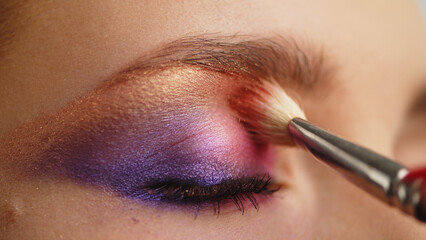 Make-up artist applies makeup to the upper eyelid, close-up.  Makeup artist applies a bright eye...