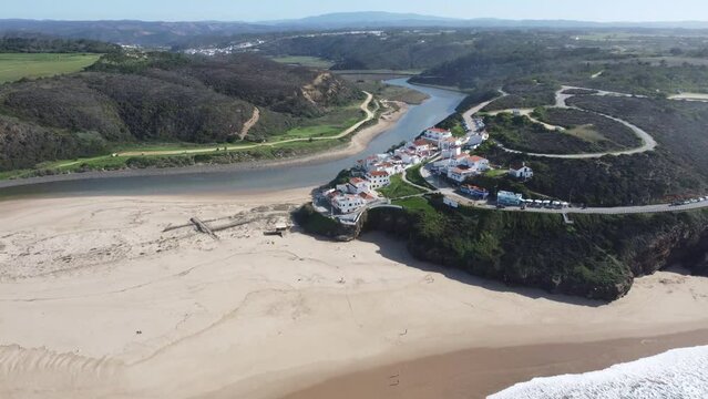 amazing odeceixe village in portugal, right at the perfet sunny beach with nice waves, droneshot