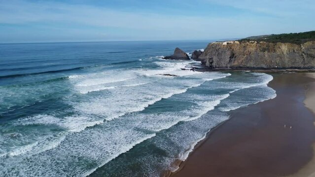 drone flies towards the waves at odeceixe beach in portugal, droneshot with sunny skies