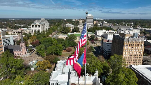 USA and Mississippi State flag with capitol in distance. Aerial in Jackson MS. Poorest state in America.