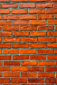 Vertical vibrant orange brick wall straight on texture with dark gray mortar