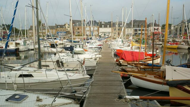 The touristic marina of Paimpol, Brittany, France, during an overcasted day. Wooden gangway in the middle, with boats vessels and yachts at both sides. 