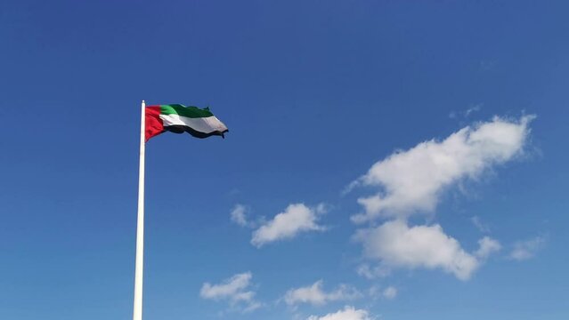 United Arab Emirates National flag waving in wind. UAE flag in blue sky background.