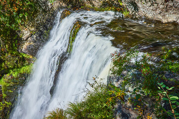 Foggy view through trees of waterfall edge