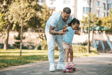 Dad teaching his daughter to ride a skate board © zinkevych