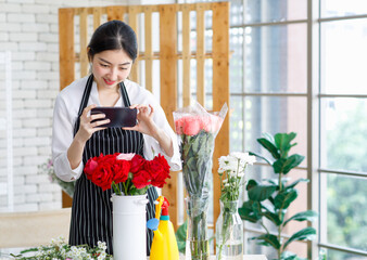 Asian young female flower shopkeeper decorator florist employee worker in apron standing smiling...