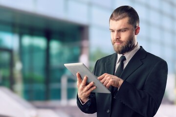 Fototapeta premium Rich business man standing outdoors and using digital table