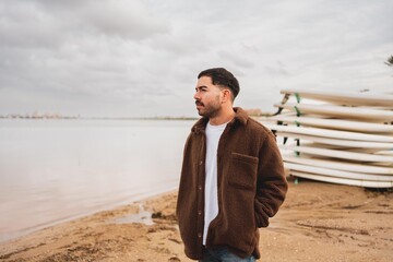 Caucasian young man by the lake in cloudy weather wearing winter clothing