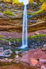 Stunning tall waterfall cliffs from below crashing into rocks