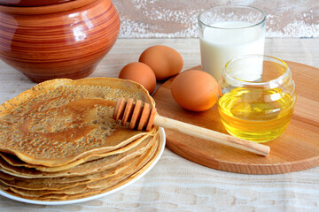fried russian blini with eggs, milk in glass and honey isolated on beige background
