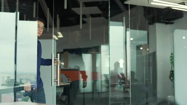 Successful Young Asian Businessman With Glasses Open The Glass Office Door In The Modern Business Centre Confident Employee IT Specialist Programmer Entering Meeting Room At Company Alone Indoors 