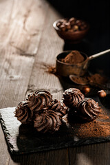 in the foreground, in a dark environment, chocolate kisses with hazelnuts and cocoa powder.