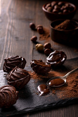 in the foreground, in a dark environment, chocolate kisses with hazelnuts and cocoa powder.