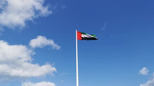 United Arab Emirates National flag waving in wind. UAE flag in blue sky background.