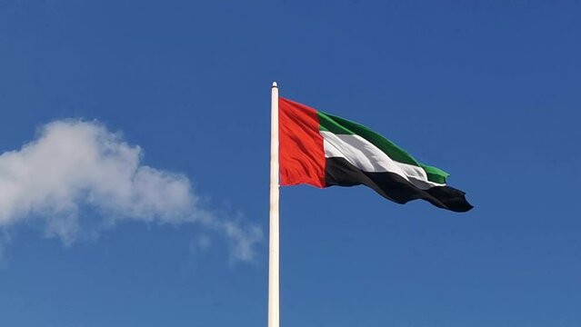 National flag of United Arab Emirates waving in wind. UAE flag in blue sky background.
