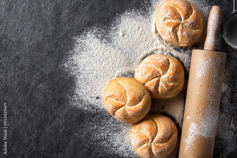 Poster Mini bun bread on a dark stone background with rolling pin top view copy space. Home baking concept