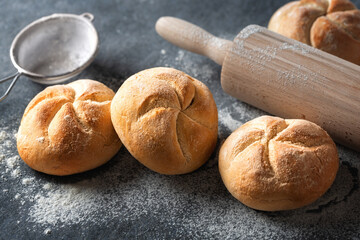 Set of fresh small bun bread on the dark table with rolling pin. Home baking concept