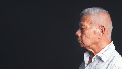 Side view of a senior man in a white shirt showing looking away while standing on a black background