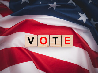 Fototapeta premium Wooden cubes with letters VOTE over the American flag background