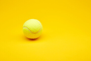 Extreme close up tennis ball isolated on the bright solid fond plain yellow background. Sport inventory and equipment concept