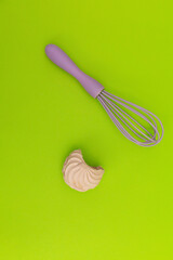 Purple whisk for the kitchen on a green background
