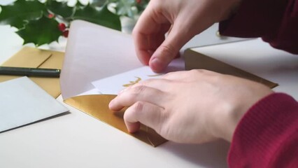 Close-up on the hands of a girl sending a thank you card in a golden envelope  to friends or family during the winter holidays, to express gratitude after receiving christmas gifts