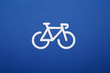 Paper applique of white bicycle lane road traffic sign made on the bright solid fond plain blue...