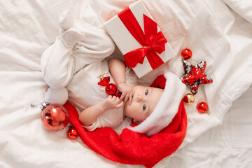 cute baby in Santa hat at home in bed. The first New Year. Christmas Gift