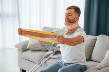 Rehabilitation exercises for arms. Man with crutches is at home indoors. Having injuries