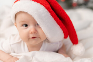 cute baby in Santa hat at home in bed. The first New Year. Christmas Gift
