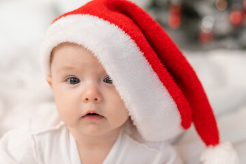 cute baby in Santa hat at home in bed. The first New Year. Christmas Gift