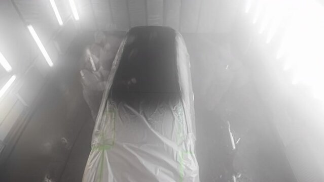 Painting the roof of a car black in an auto body paint booth - time lapse