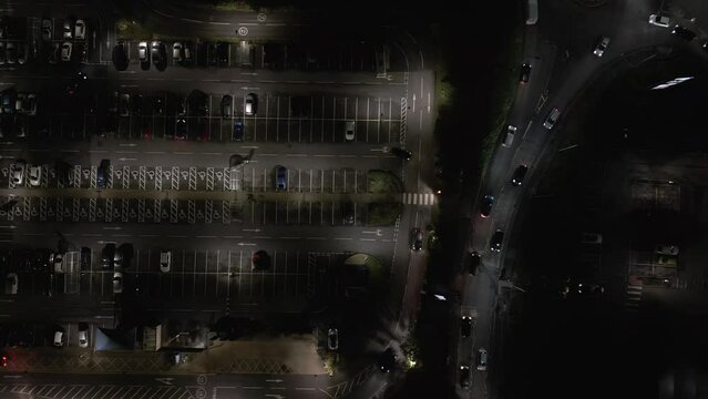 Night aerial top down view of a carpark with busy road