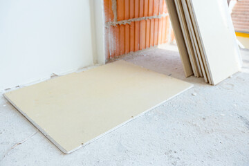 Pieces of gypsum boards are waiting to be installed on the walls of unfinished building