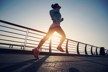 Fitness woman runner running on seaside bridge