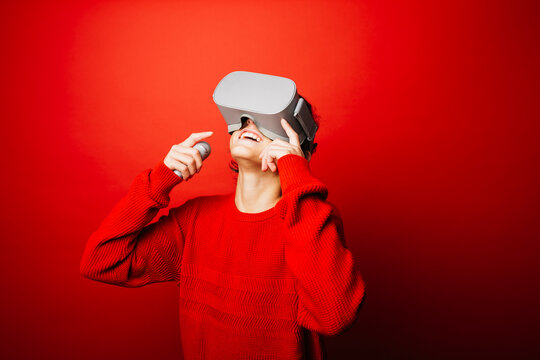 Studio portrait of a pre-adolescent boy with virtual reality glasses over a red background - Powered by Adobe