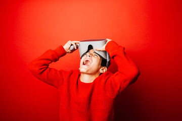 Studio portrait of a pre-adolescent boy with virtual reality glasses over a red background