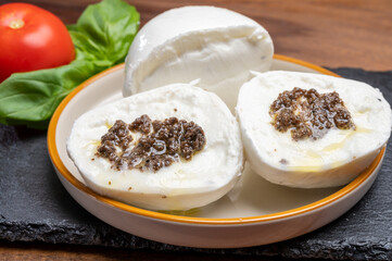 White balls of Italian soft cheese Mozzarella di Bufala Campana stuffed with black truffles mushrooms
